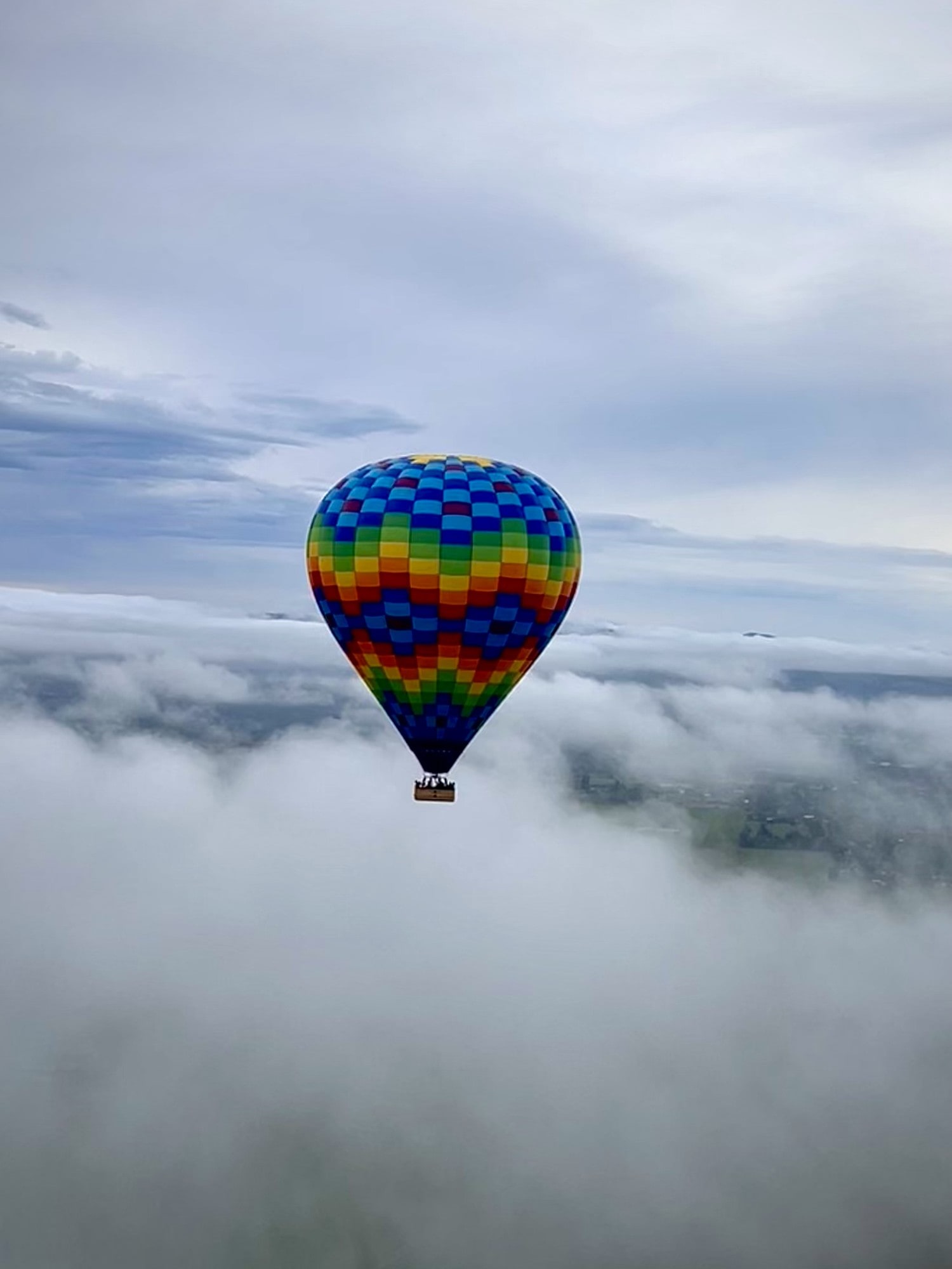 A hot air balloon flying above a layer of clouds